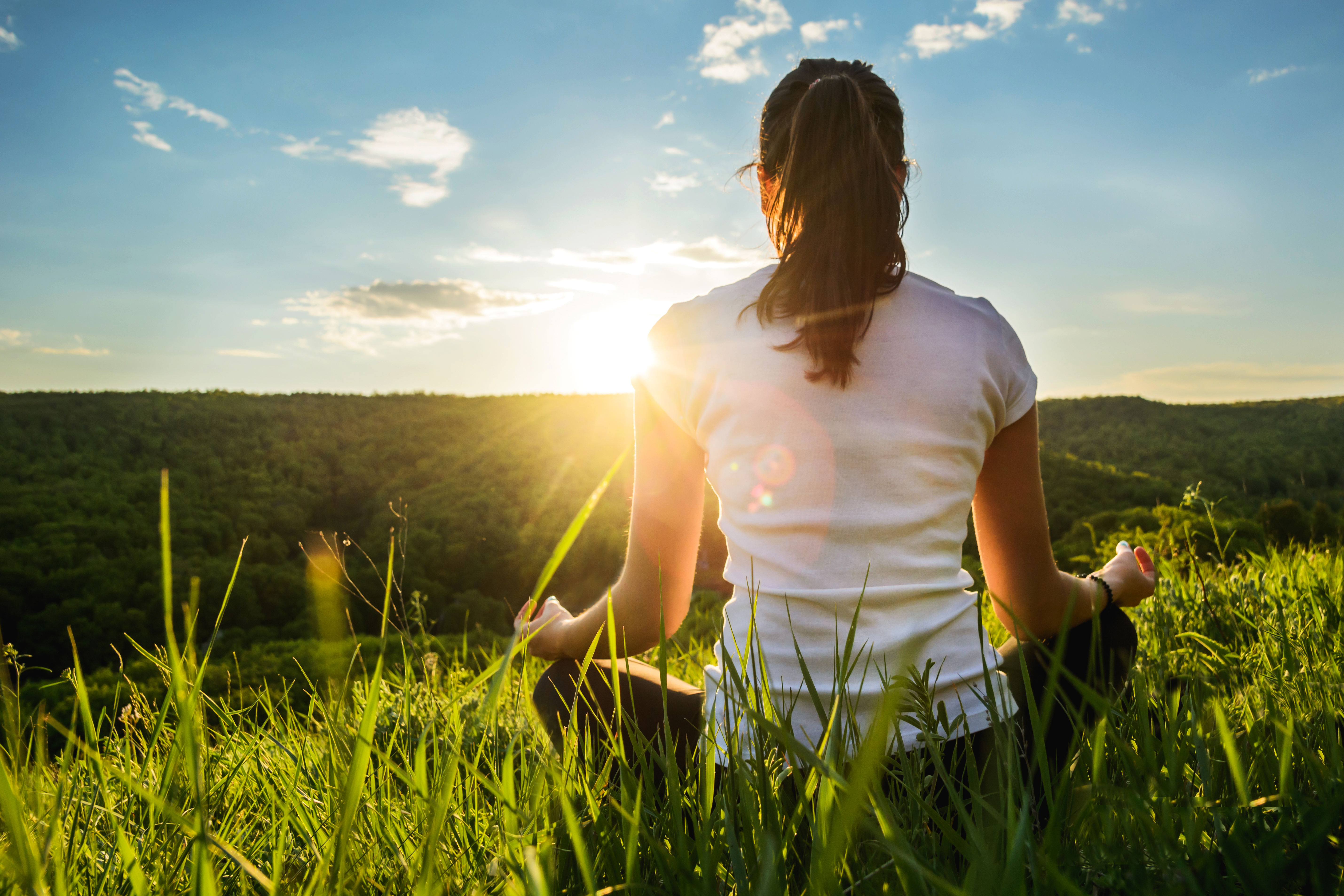 woman practices yoga on the hill during sunset